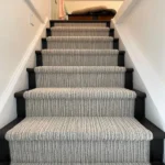 A straight-on view looking up a wooden staircase painted dark charcoal