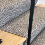 Angled view of textured gray runner on light wood steps