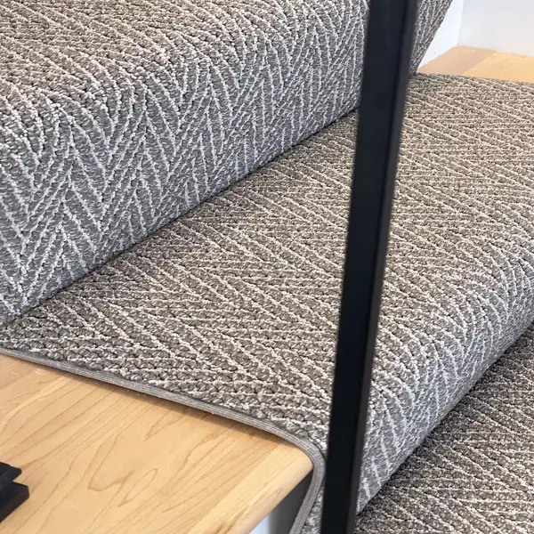 Angled view of textured gray runner on light wood steps