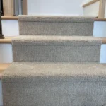 Beige carpet runner on wood stairs, front view