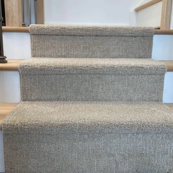 Beige carpet runner on wood stairs, front view