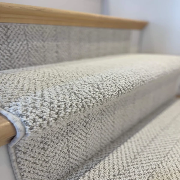 Close-up of gray patterned carpet on a stair nose