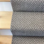 Close-up of gray patterned carpet runner on wood stairs