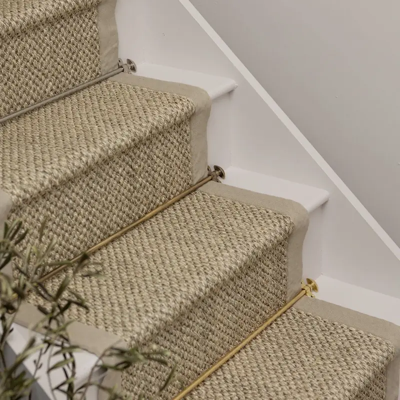 Close-up of sisal stair runner with brass carpet rods.