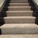 Dark wood staircase featuring a ribbed carpet runner.