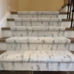 Front view of patterned carpet runner on wood stairs.