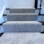 Gray patterned carpet runner on dark wood stairs
