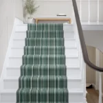 Green and white striped Wool Biscayne stair runner on white stairs.
