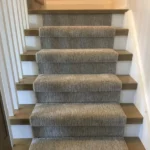 Light wood stairs with a grey textured carpet runner