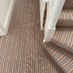 Multi-colored Wool Mississippi striped carpet on a landing and stairs.