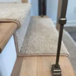 Side profile of carpet runner on wood stairs.