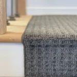 Side profile of grey carpet runner over a stair nose