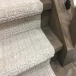 Side view of beige carpet runner and wood stairs