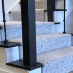 Side view of stairs with carpet and black spindles.