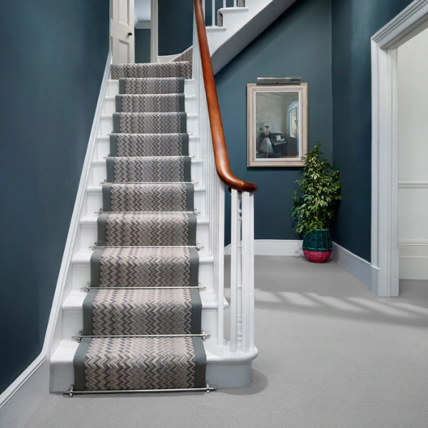 Staircase with zigzag patterned carpet runner in gray and beige tones