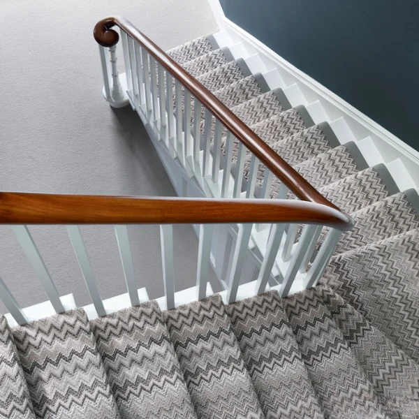 Staircase with zigzag patterned carpet runner in gray and beige
