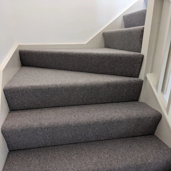 Tight loop grey Berber carpet on modern stairs.
