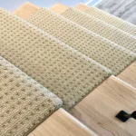 Top-down view of textured beige carpet stair treads