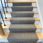 Wide view of gray herringbone runner on wooden staircase