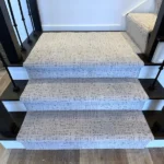 Wide view of modern stairs with gray carpet runner.